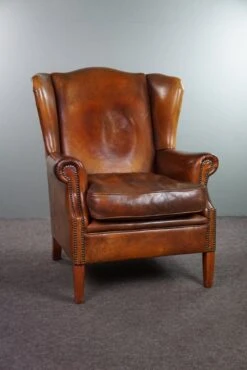 Very Rugged Wingback Armchair Made Of Cognac-colored Sheep Leather Finished With Decorative Nail Hea 19 Very Rugged Wingback Armchair Made Of Cognac-colored Sheep Leather Finished With Decorative Nail Hea -Chairly Shop 87aa0ba2 18ea 4ee2 8e01 90175d4b8091