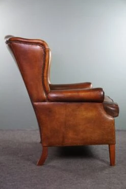 Very Rugged Wingback Armchair Made Of Cognac-colored Sheep Leather Finished With Decorative Nail Hea